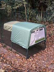 An Eglu Cube chicken coop wrapped in a green extreme temperature blanket