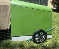 A green chicken coop with wheels