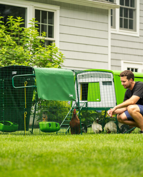 Man kneeling down looking into his Eglu Cube chicken coop with 10 year warranty