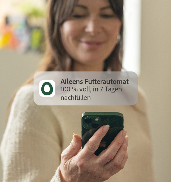 Frau empfängt Omlet app feed level benachrichtigung auf ihrem telefon