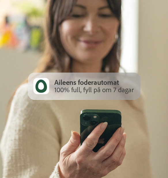 Kvinna som får Omlet appens meddelande om matningsnivå till sin telefon