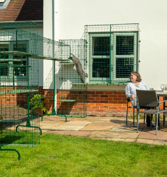 A lady sat next to her cats in the Omlet catio enclosure