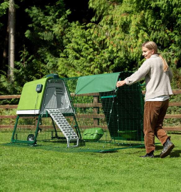 woman easily moving the eglu go chicken coop around her garden