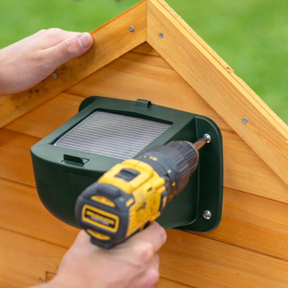 The Omlet smart fan being attached to the inside of a wooden chicken coop