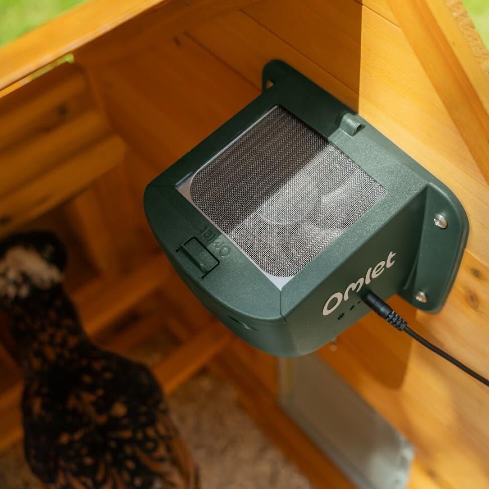 A close up of the smart fan in a wooden chicken coop
